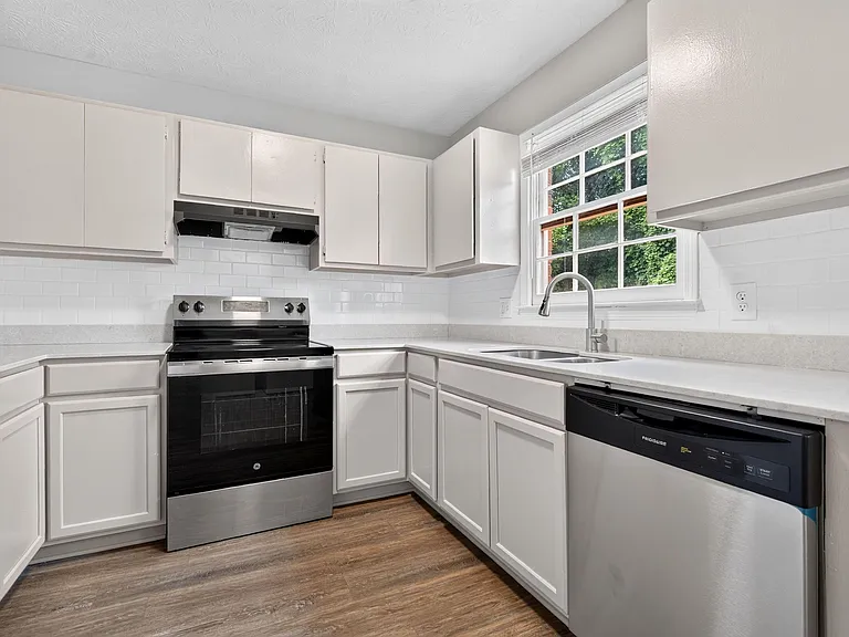 U-shaped kitchen with ample cabinet storage, long counters, dishwasher, and a window over the sink for natural light.
