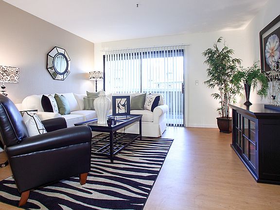 Staged living room with hardwood style flooring and sliding door leading to balcony.
