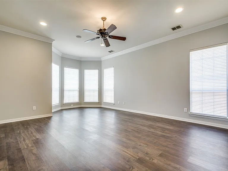 Spacious room featuring wood-finish flooring, a bay window configuration, crown molding, a ceiling fan, and recessed lighting