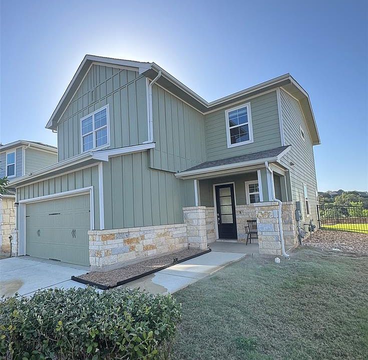 Craftsman-style home with board and batten siding, stone siding, covered porch, driveway, and an attached garage