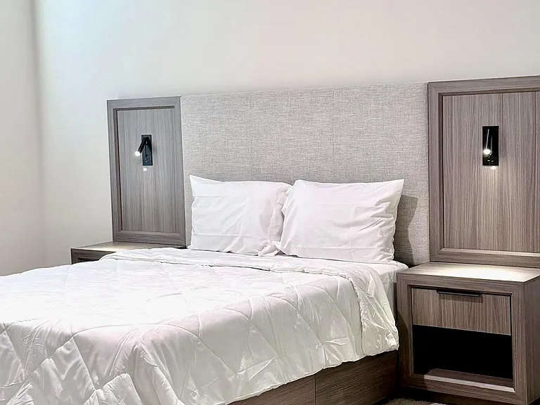 Furnished bedroom with a platform bed, built-in headboard lighting, and nightstands for convenient storage.