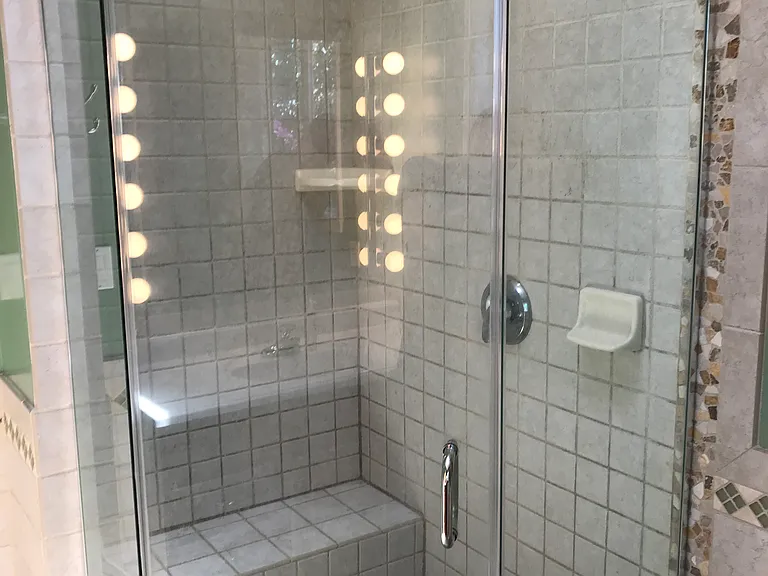 Custom shower stall with marble tile floor, bench and 3/8" glass surround.