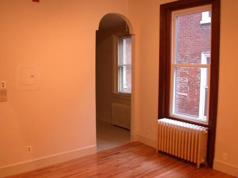living room, oval doorway into kitchen, window in living room, ceiling fan with lights. hardwood floors