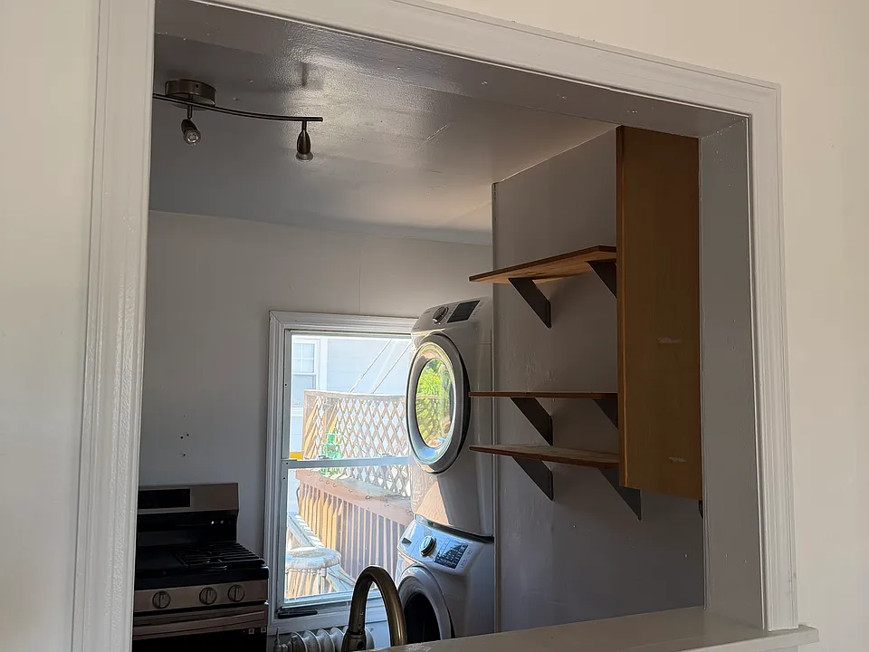 View of kitchen from living room wall cut out. showing washer dryer