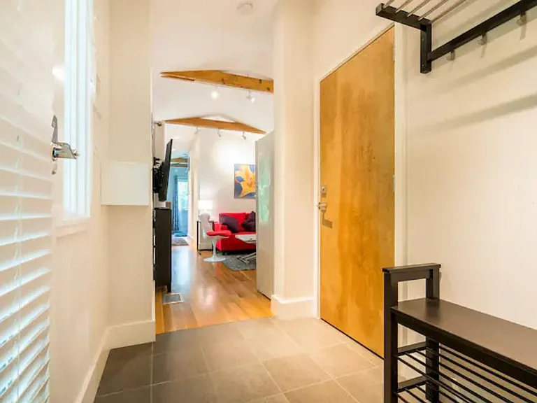 The entry is welcoming and spacious and shows a view through the apartment. The door shown is always locked from the other side with another soundproof door nested in the frame. It leads to the owners' part of the house. A tenant could fit a bike here.