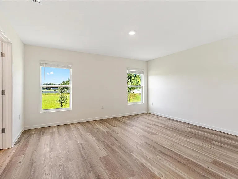 Primary bedroom with two windows overlooking the landscape