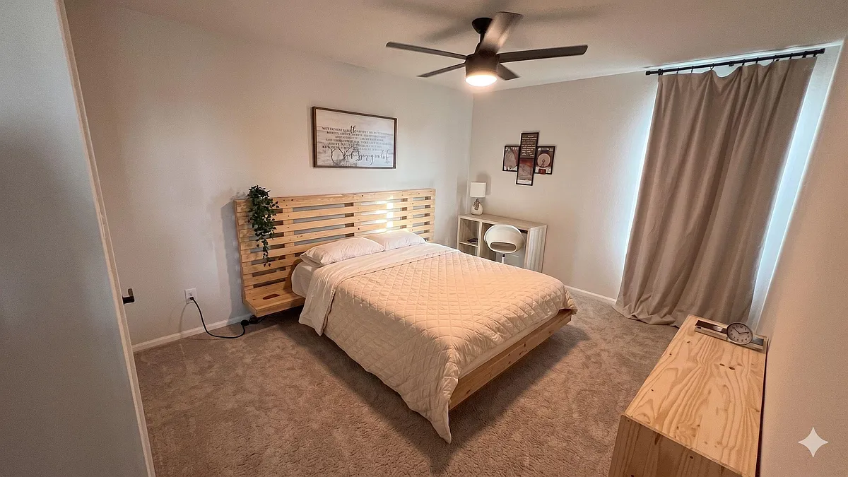 Spacious bedroom with a platform bed, ceiling fan, and soft carpeting, plus a desk nook and large window with curtains. - Raphael Cv
