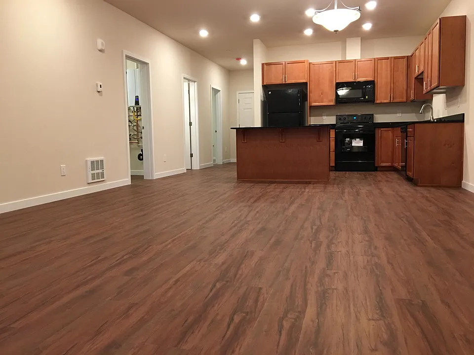 Bright open-concept kitchen and living area featuring durable LVP flooring, center island, ample cabinet space, cozy fireplace, and sliding glass doors that fill the space with natural light.