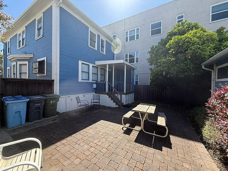 Large paved backyard with picnic table and chairs