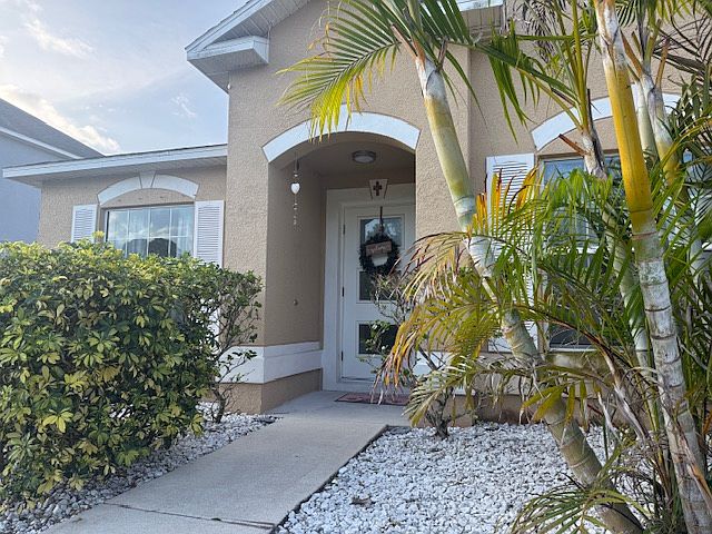 Beautiful curb appeal with inviting front entrance and tropical landscaping