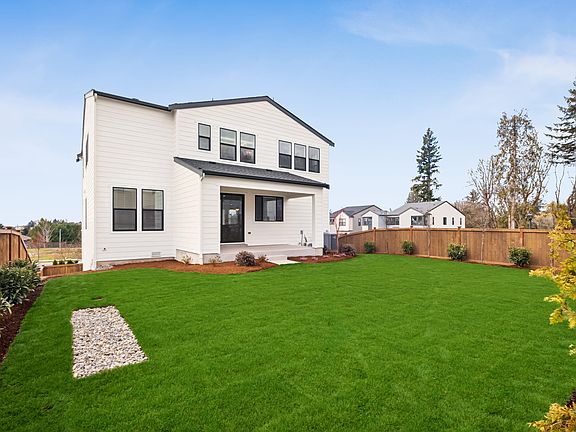A well-manicured lawn with a gravel path leads to a modern, two-story house with a white exterior an