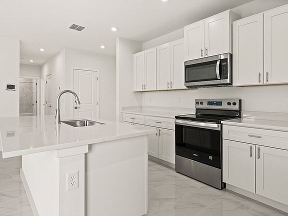 Bright kitchen with white cabinetry, quartz countertops, and center island in the Castaway model