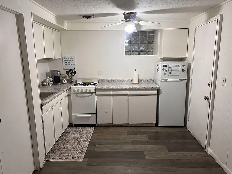 Efficient U-shaped kitchen with ample cabinet storage, laminate counters, gas range, and compact fridge for easy meal prep.