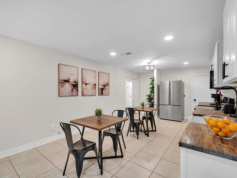 Eat-in kitchen with stainless refrigerator, generous counter space, and two dining tables for shared meals or work.