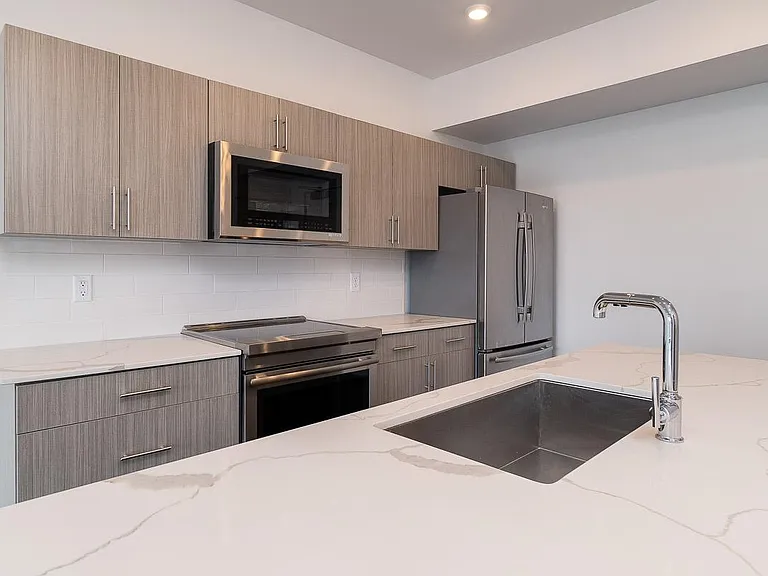 Clean White Tile Backsplash with Chrome Hardware.