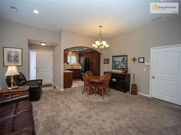 View of living/dining combo, updated kitchen, front door to the left, door to garage on right.