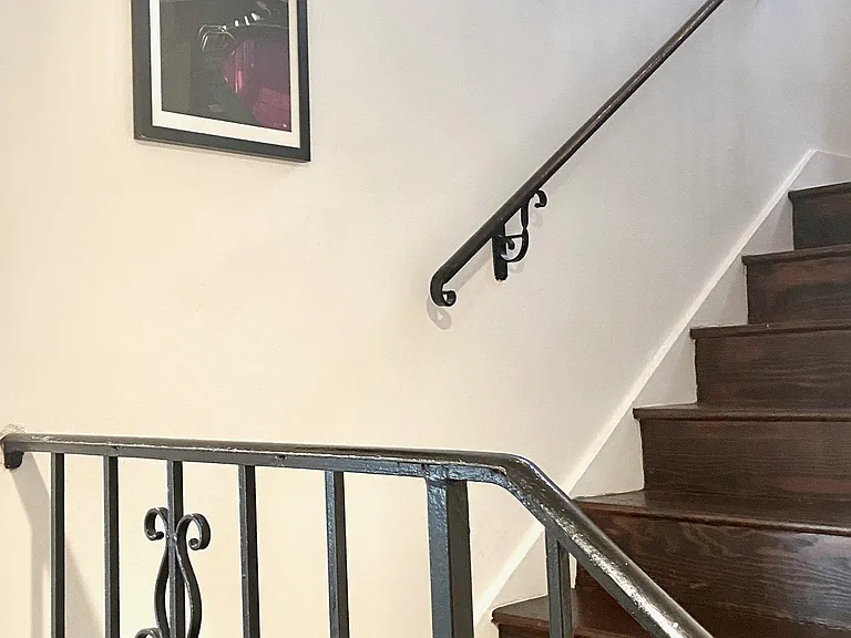Stairwell leading to the lower level with bedrooms, the main bathroom, laundry, and deck access.