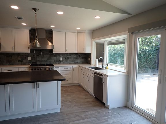 Kitchen with bay window and solar shades, recessed lighting, patio door to backyard