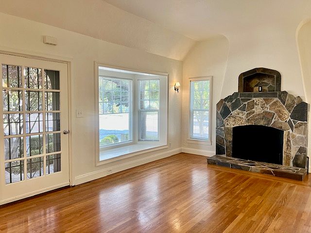 Very spacious living room, with wood floors, lots of windows, and wall sconces in addition to a very large ceiling light