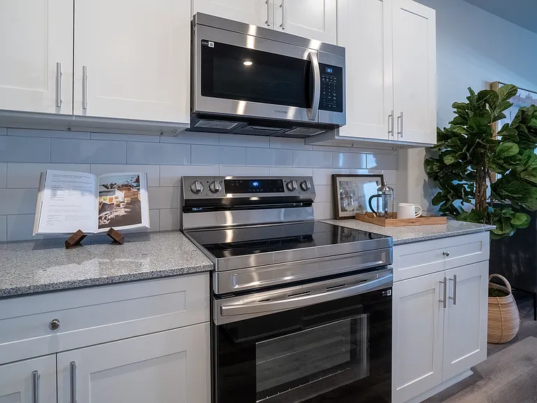Kitchen with a stainless steel stove/oven and microwave. This kitchen has granite countertops and subway tile backsplash.