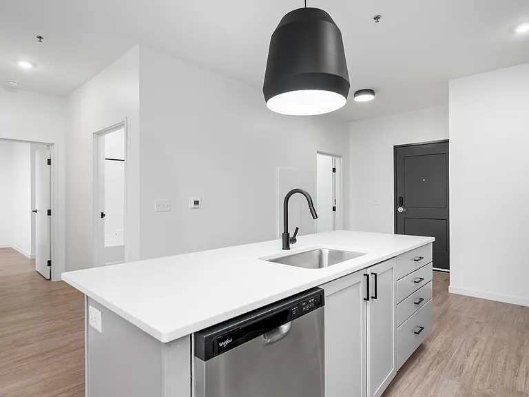 Modern kitchen with sleek white countertops, stainless steel appliances, and elegant black pendant lighting offering a contemporary look. Modern kitchen with sleek white countertops, stainless steel appliances, and elegant black pendant lighting offering