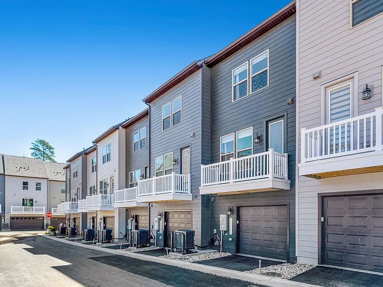 Rear view of the townhome highlighting outdoor space, garage access, and modern exterior design.