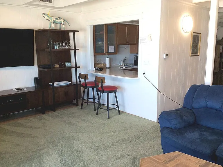 Living room leading to kitchen area with breakfast nook and seating.