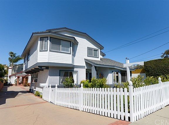 A shot of the driveway and white picket fence.  On the left side you can see the garden window in the kitchen.