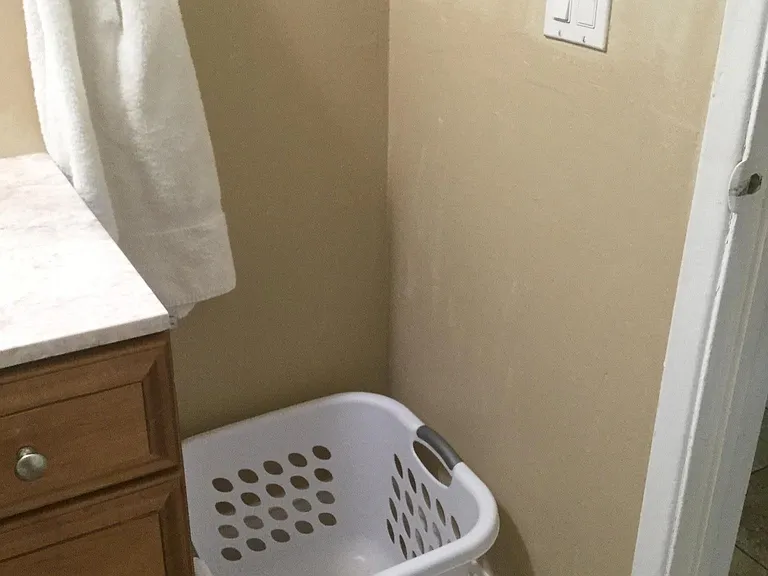 Hallway bathroom has space for laundry basket too.