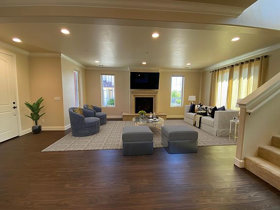 Large, modern living room with gas fireplace, high ceilings and crown molding.