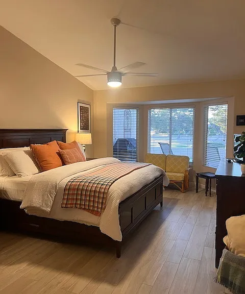 Oversized primary bedroom with designer bed, nightstands and dresser. Sitting area looks out to patio and golf course.