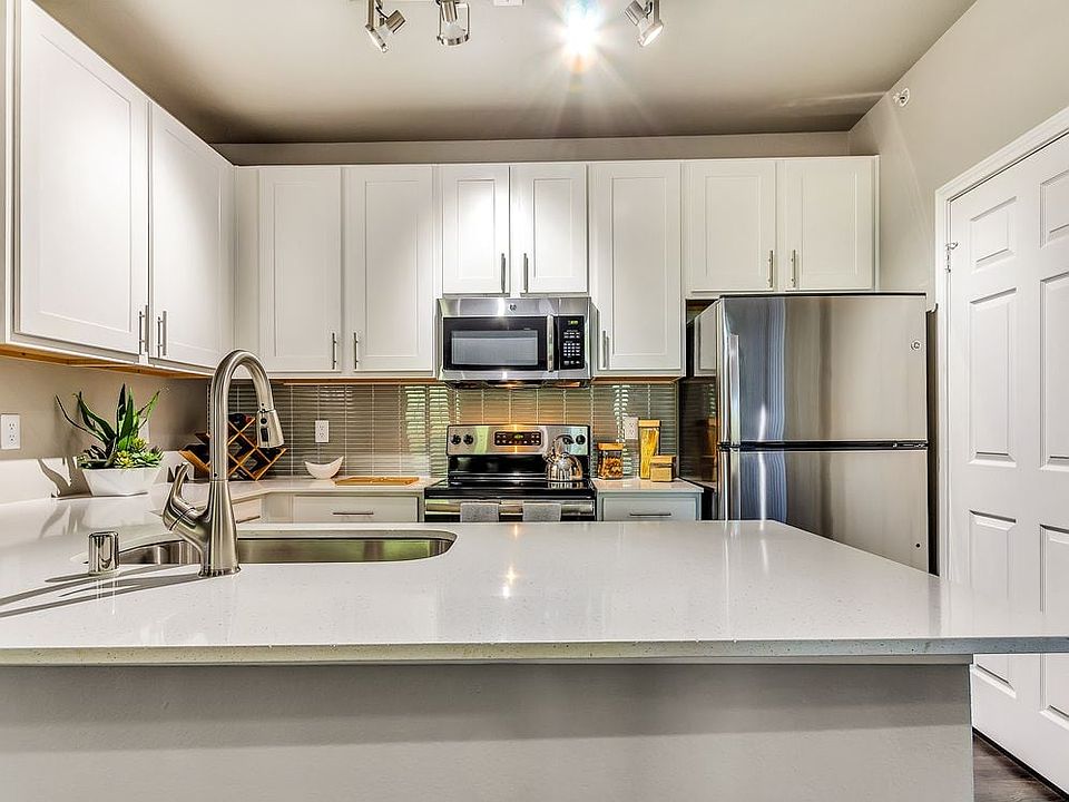 Classic Package II kitchen with stainless steel appliances, white quartz countertop, tile backsplash, white cabinetry, and hard surface flooring