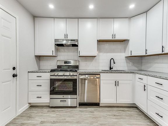 Kitchen featuring white cabinetry, appliances with stainless steel finishes, light stone countertops, tasteful backsplash, and recessed lighting