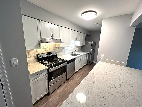 Bright white kitchen with stainless steel appliances, shaker cabinets and quartz countertops