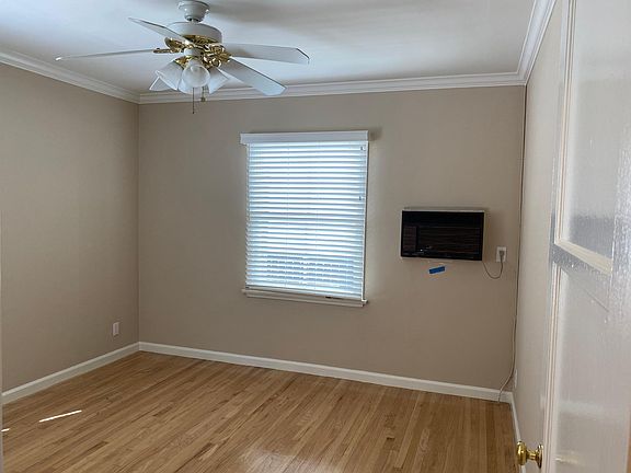 View of bedroom/A.C in wall/new faux wood blinds/ ceiling fan/crown molding/ refinished hardwood floors.
