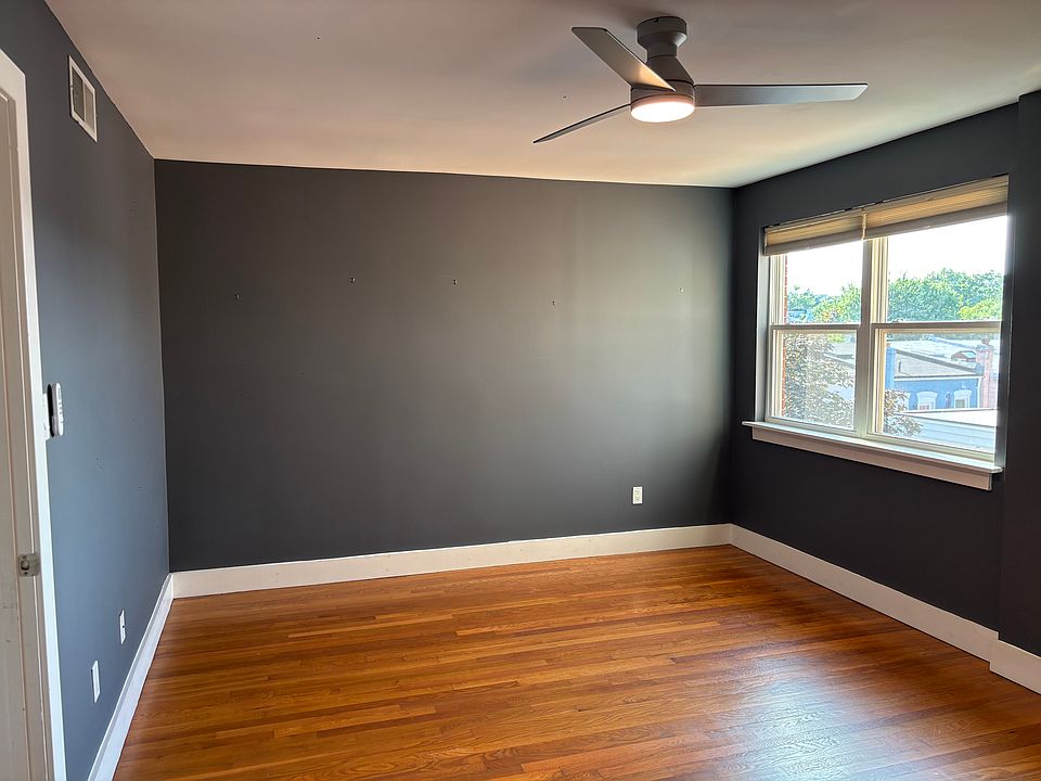 Very large bedroom with ceiling fan and big window.