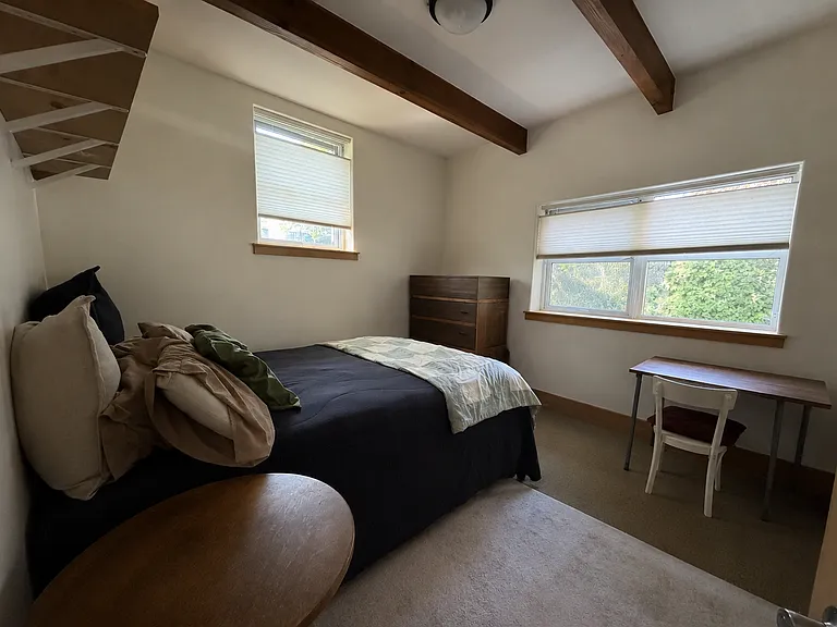 Downstairs bedroom with three windows, exposed beams, a roomy alcove, and plenty of closet space.