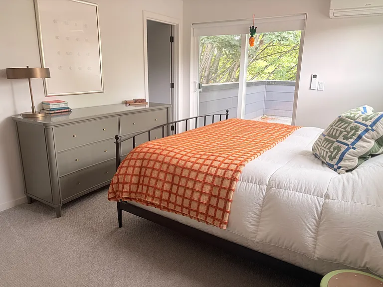 Primary bedroom on the top floor with walk-in closet, en suite bathroom with rain shower, and a private terrace in the trees
