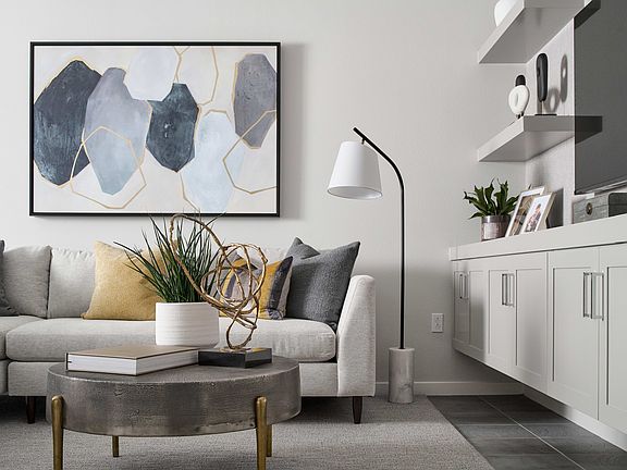 A modern and minimalist living room with a gray sectional sofa, a round coffee table, and a large ab