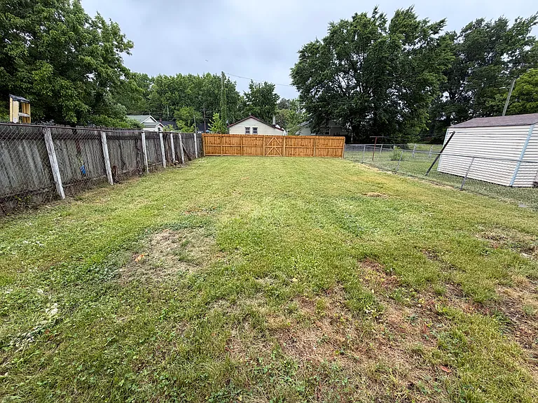 large fenced in back yard, with gate to alley parking