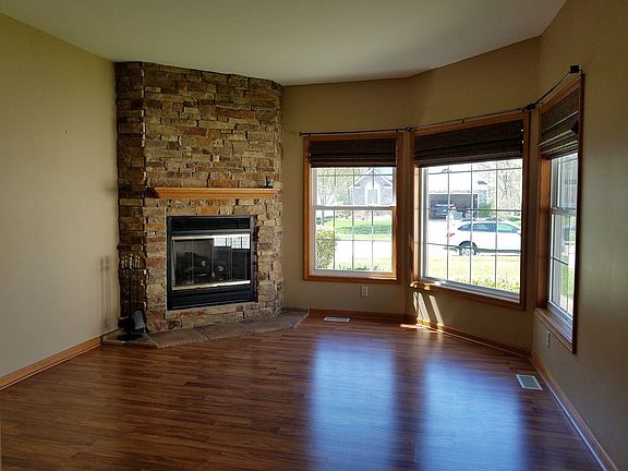 Living room with stone gas fireplace and laminate floor.