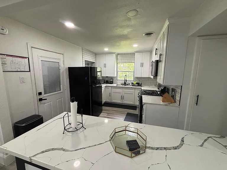 Updated kitchen with quartz-look island, ample white cabinetry, subway-tile backsplash, and full appliance set.