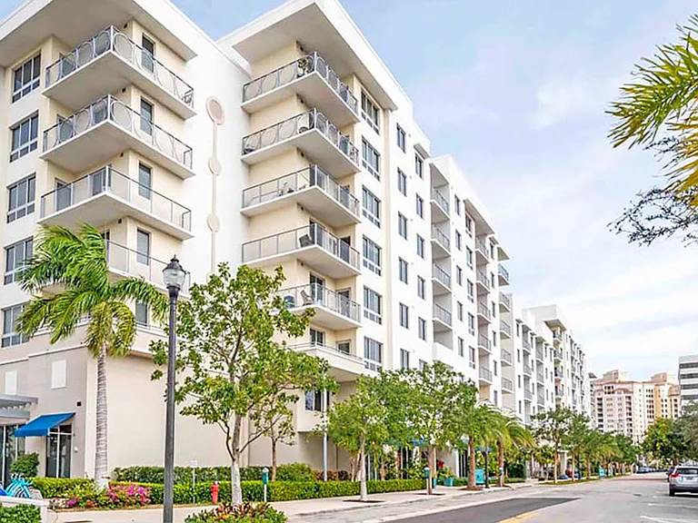 Luxury apartment community exterior with modern mid-rise building, balconies, and landscaped streetscape