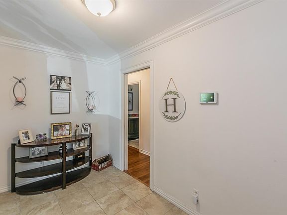 Hall with light tile patterned flooring and ornamental molding
