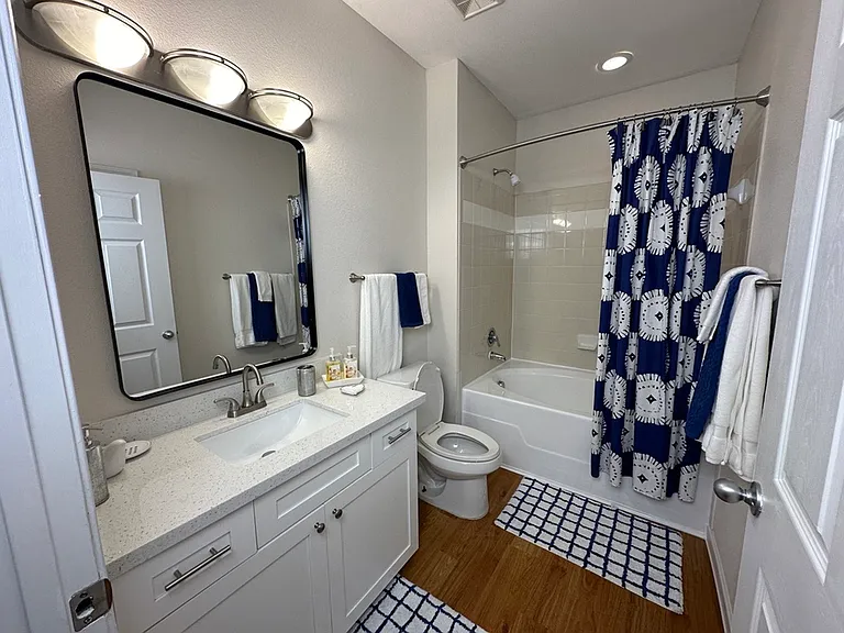 Modern bathroom featuring a sleek vanity with a large mirror, elegant lighting, and a stylish shower curtain for a fresh and inviting atmosphere. Modern bathroom featuring a sleek vanity with a large mirror, elegant lighting, and a stylish shower curtain