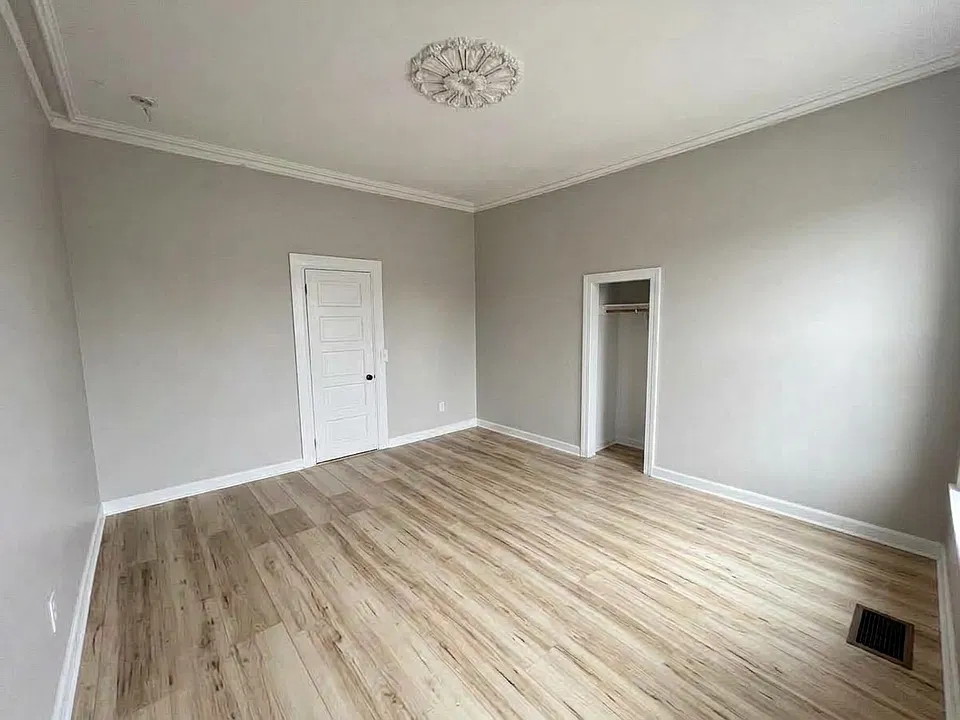 Bedroom 1 rear-facing photo, vacant. Spacious bedroom with multiple windows, abundant natural light, and plenty of usable floor space.