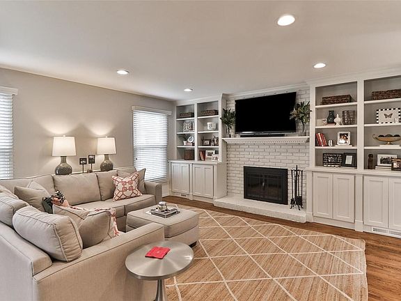 Family room with newly installed cabinetry and bookshelves and freshly painted fireplace with glass doors