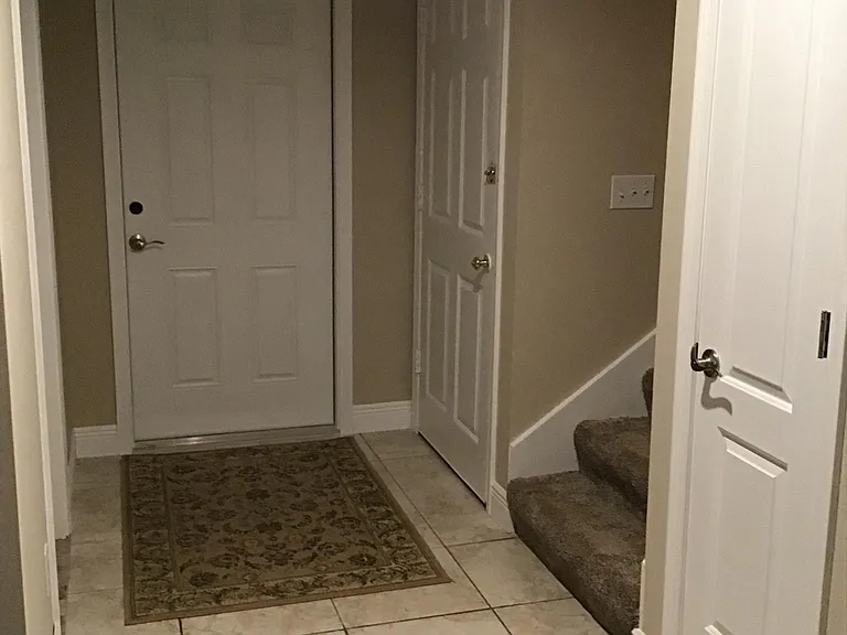 Bottom of stairs and foyer. Door on right is main entrance. Door on left goes to garage.