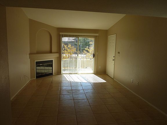 Tile living room with gas fireplace and sliding door to balcony.