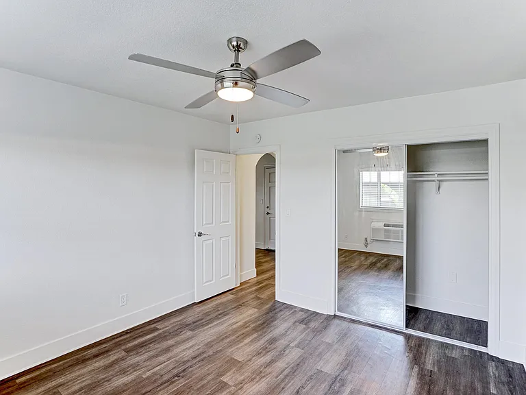 A room with a ceiling fan and wooden floors.